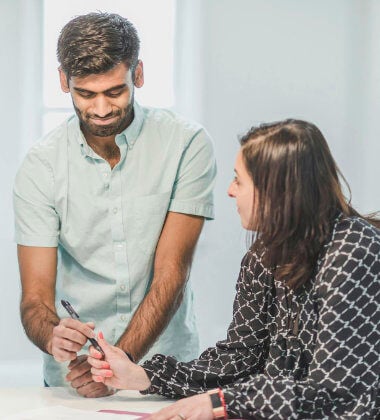 Man signing a document while a woman watches on