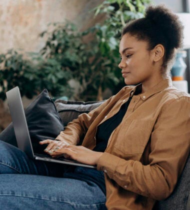 A woman using a laptop whilst sitting on a sofa