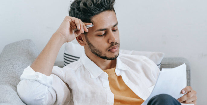 A man sits on a sofa reading a report